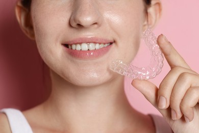 Photo of Smiling woman with dental aligner on pink background, closeup