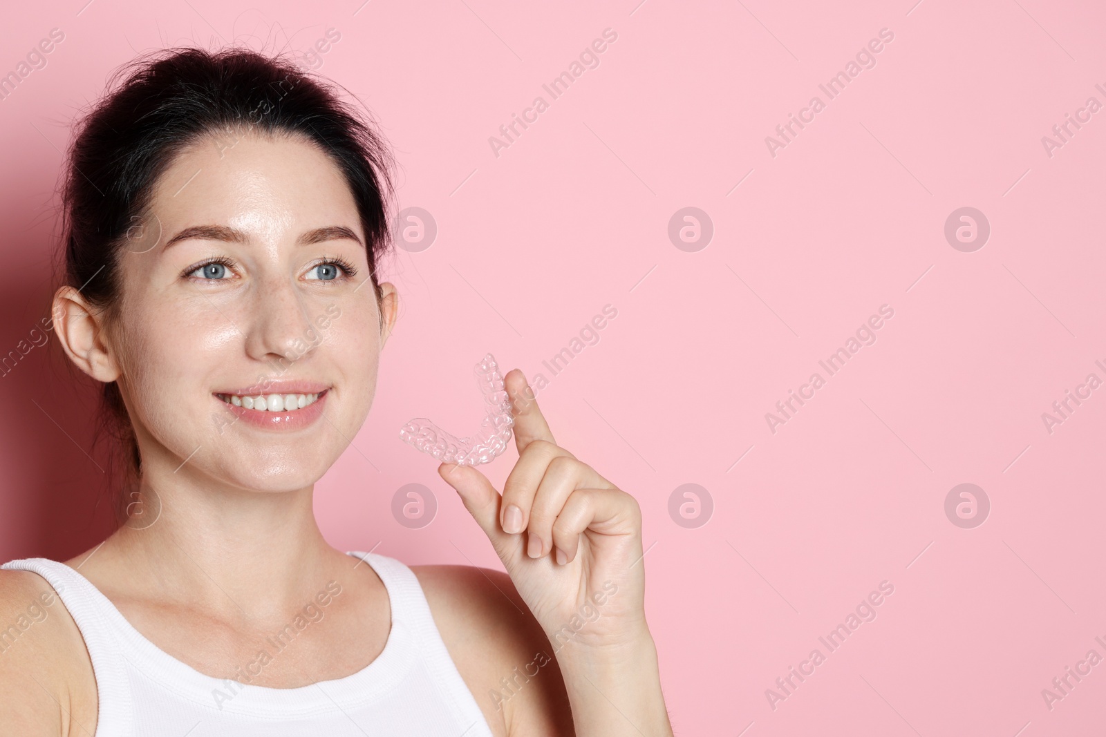 Smiling woman with dental aligner on pink background. Space for text Photo of Smiling woman with dental aligner on pink background. Space for text