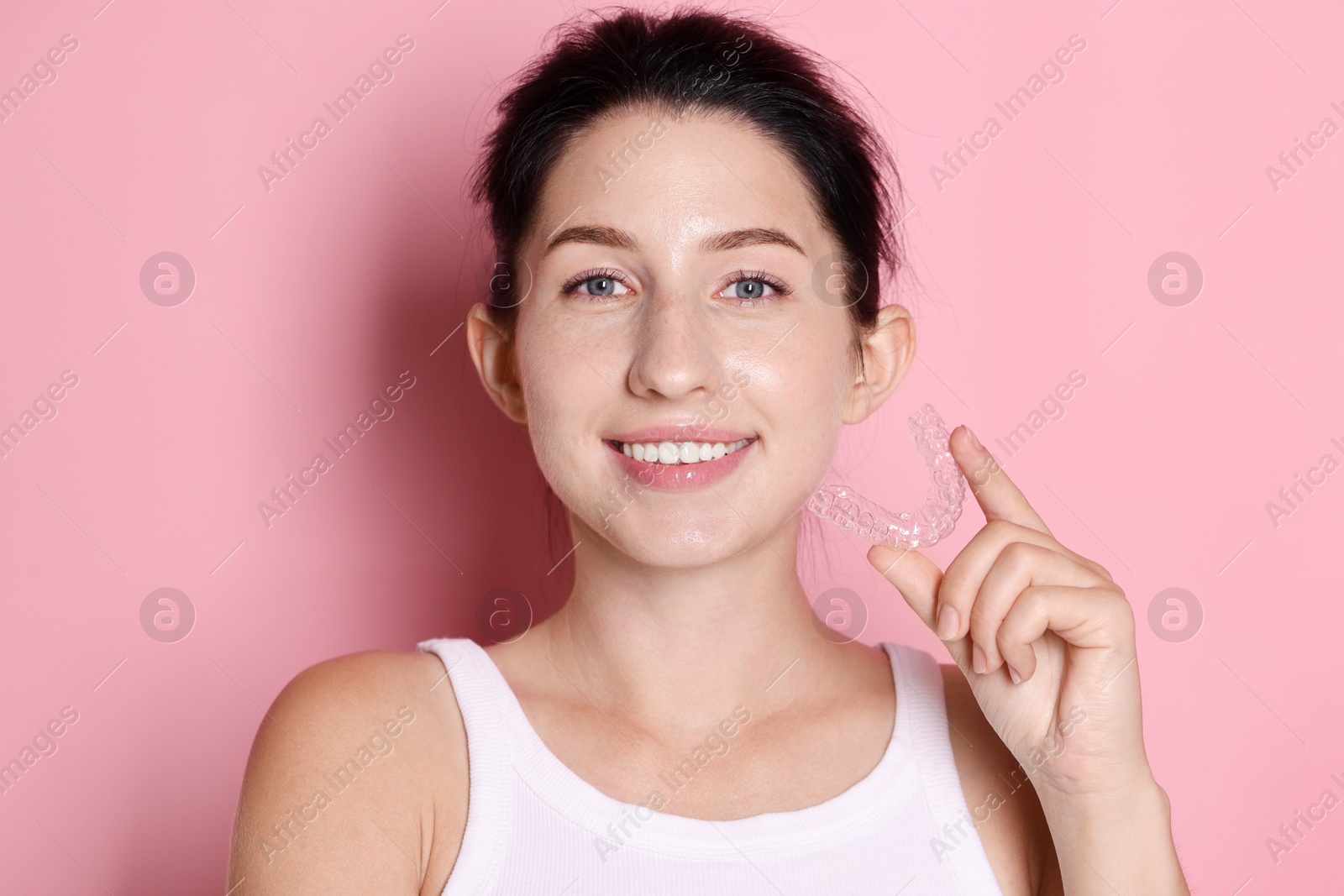 Portrait of smiling woman with dental aligner on pink background Photo of Portrait of smiling woman with dental aligner on pink background