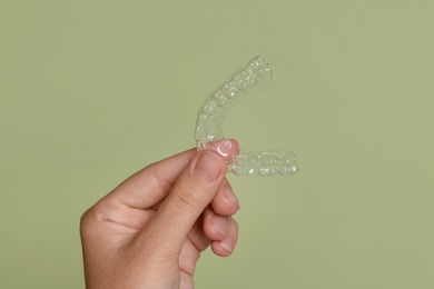 Photo of Woman with dental aligner on green background, closeup