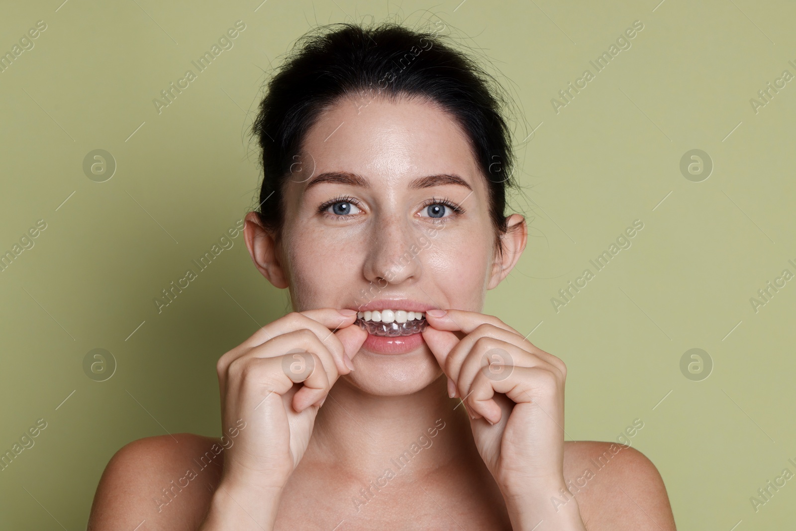 Beautiful woman wearing dental aligner on green background Photo of Beautiful woman wearing dental aligner on green background