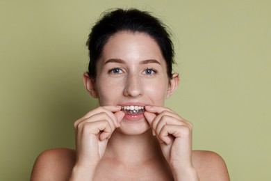 Photo of Beautiful woman wearing dental aligner on green background
