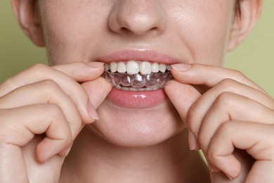 Photo of Woman wearing dental aligner on green background, closeup