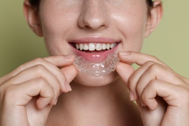 Photo of Smiling woman wearing dental aligner on green background, closeup