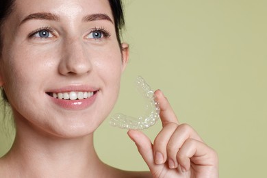 Photo of Smiling woman with dental aligner on green background, closeup