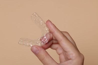 Photo of Woman with dental aligner on beige background, closeup