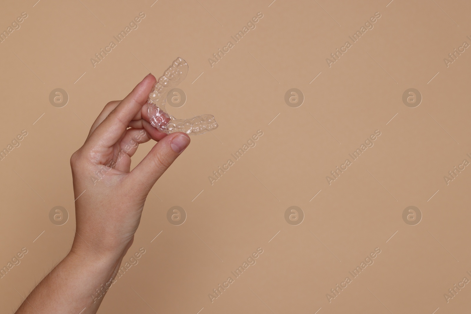 Woman with dental aligner on beige background, closeup. Space for text Photo of Woman with dental aligner on beige background, closeup. Space for text