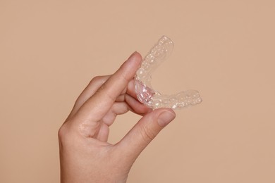Photo of Woman with dental aligner on beige background, closeup
