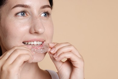 Photo of Woman wearing dental aligner on beige background, closeup. Space for text