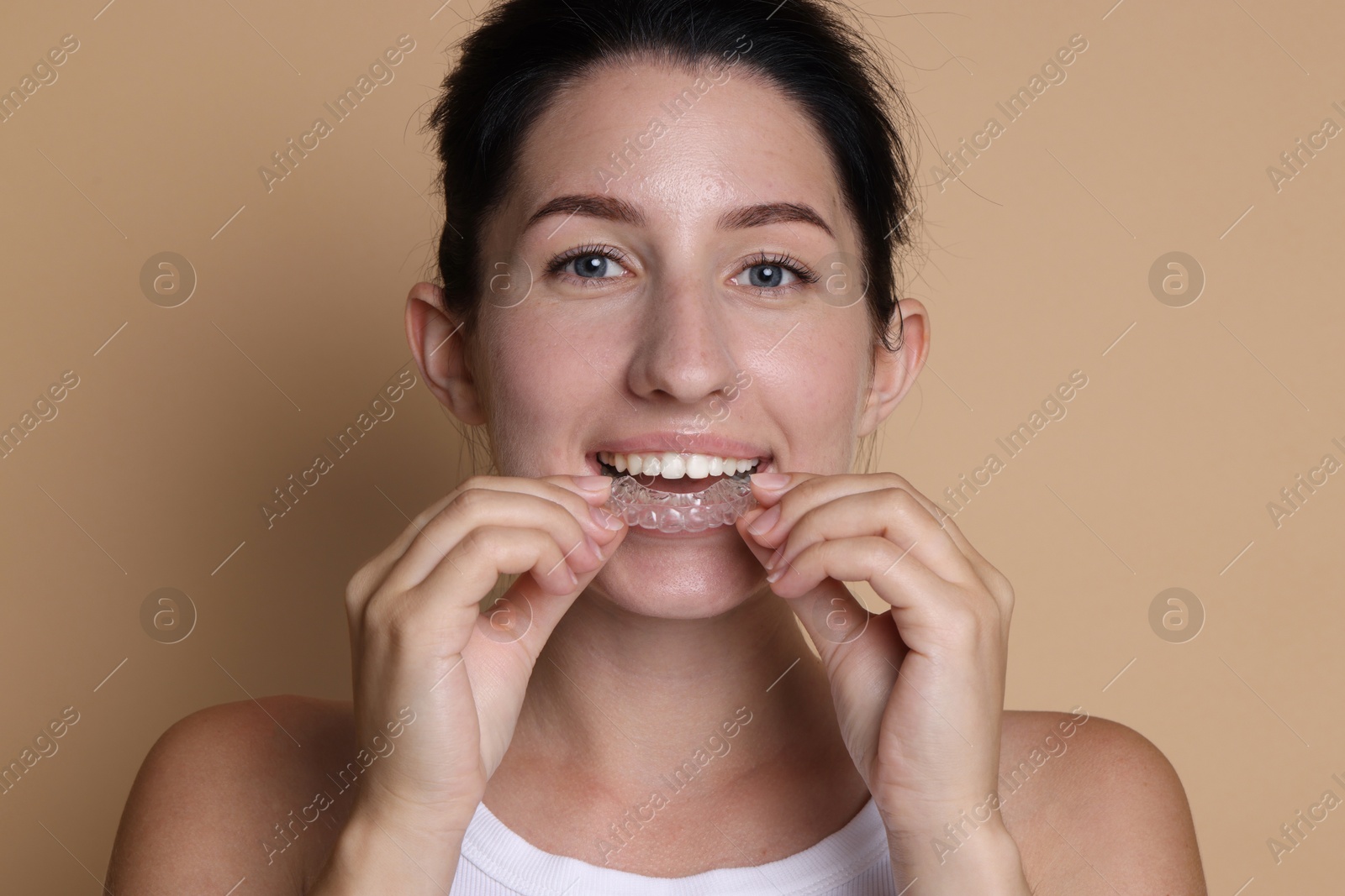 Young woman wearing dental aligner on beige background Photo of Young woman wearing dental aligner on beige background