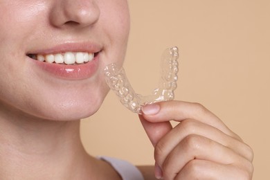 Photo of Smiling woman with dental aligner on beige background, closeup