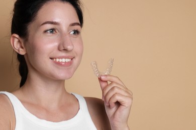 Photo of Smiling woman with dental aligner on beige background, closeup. Space for text