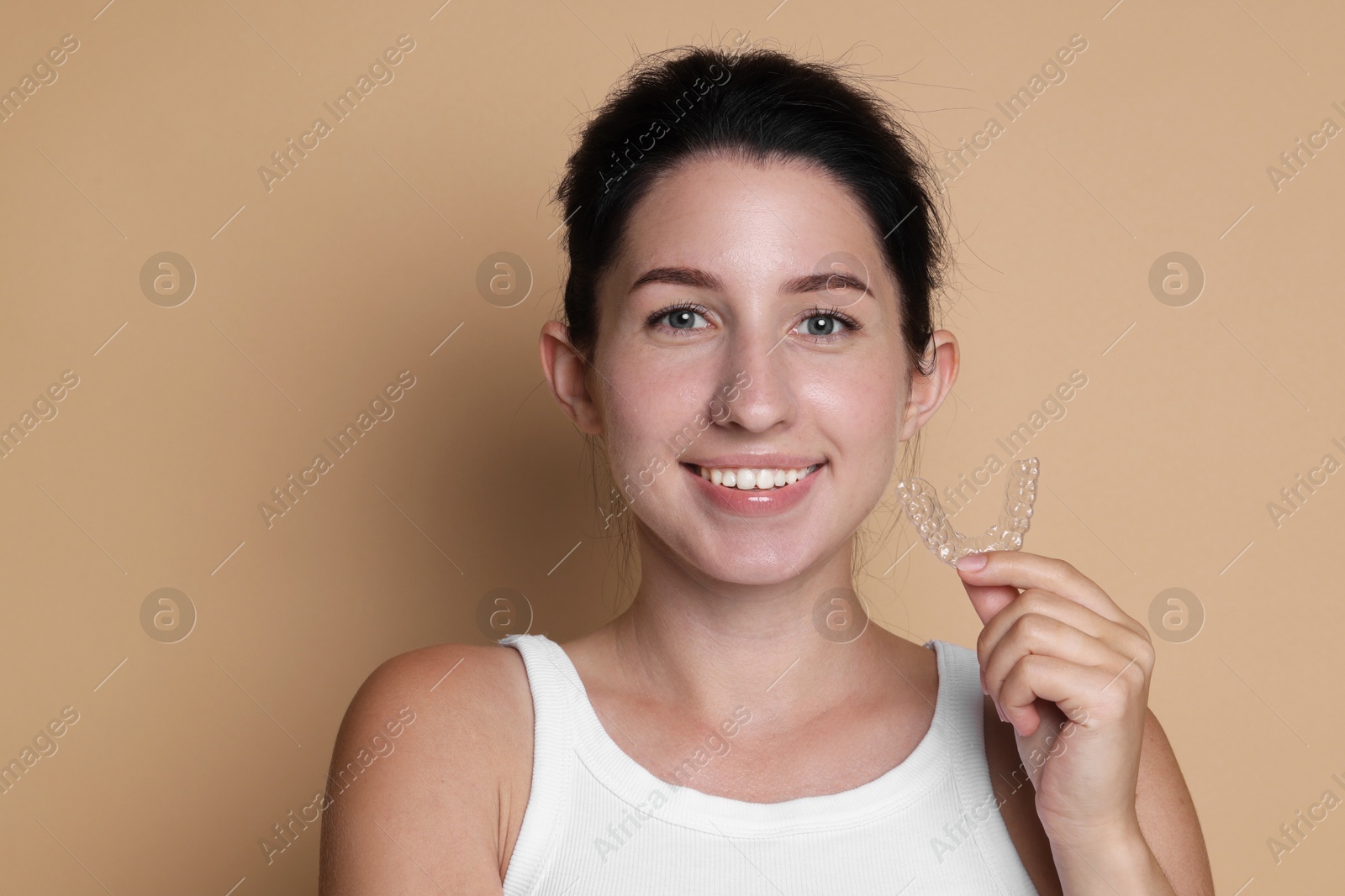 Portrait of smiling woman with dental aligner on beige background Photo of Portrait of smiling woman with dental aligner on beige background