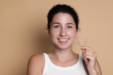 Photo of Portrait of smiling woman with dental aligner on beige background