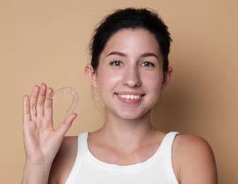 Photo of Portrait of smiling woman with dental aligner on beige background