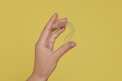 Photo of Woman with dental aligner on yellow background, closeup