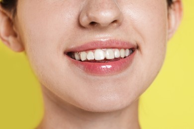 Photo of Smiling woman with dental aligner on yellow background, closeup