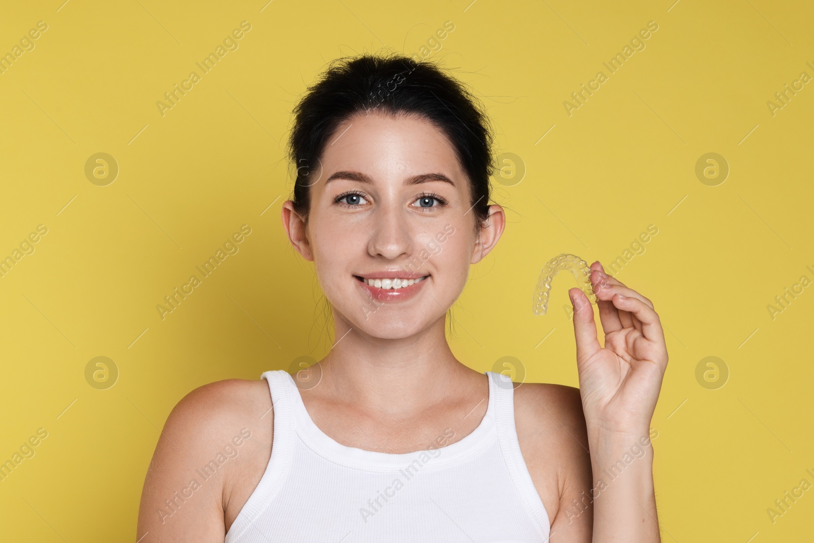 Portrait of smiling woman with dental aligner on yellow background Photo of Portrait of smiling woman with dental aligner on yellow background