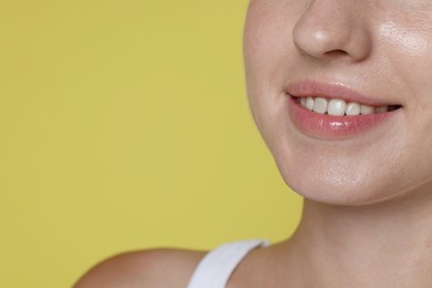 Photo of Smiling woman after dental aligners treatment on yellow background, closeup. Space for text