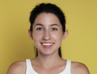 Photo of Portrait of smiling woman after dental aligners treatment on yellow background