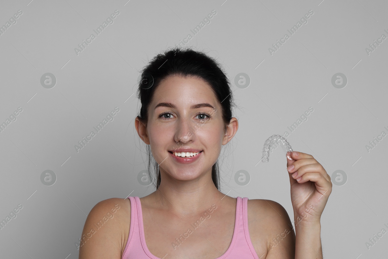 Portrait of smiling woman with dental aligner on grey background Photo of Portrait of smiling woman with dental aligner on grey background