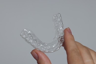 Photo of Woman with dental aligner on grey background, closeup