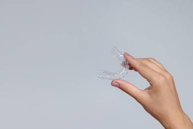 Photo of Woman with dental aligner on grey background, closeup. Space for text