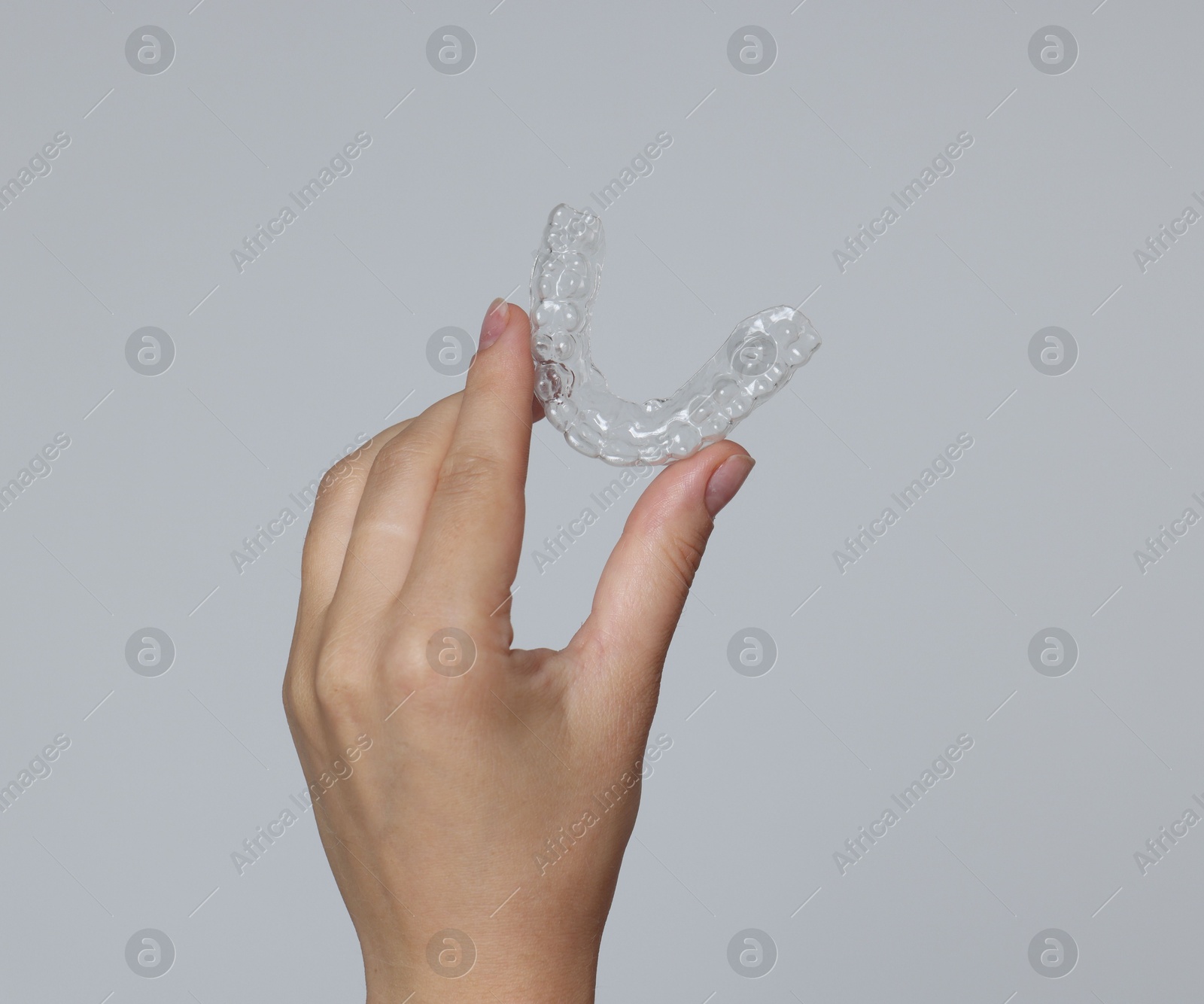 Woman with dental aligner on grey background, closeup Photo of Woman with dental aligner on grey background, closeup