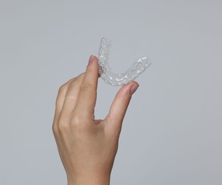 Photo of Woman with dental aligner on grey background, closeup