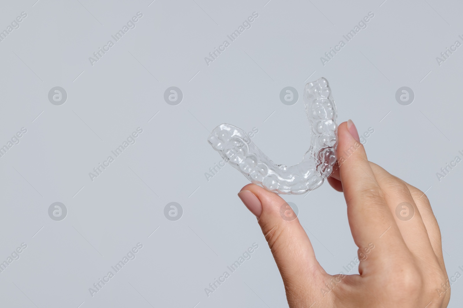 Woman with dental aligner on grey background, closeup. Space for text Photo of Woman with dental aligner on grey background, closeup. Space for text