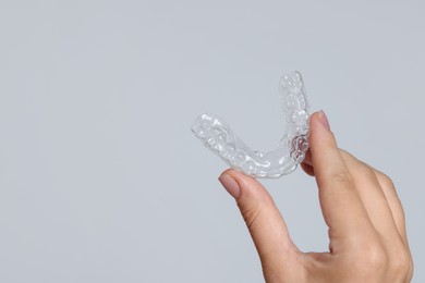 Photo of Woman with dental aligner on grey background, closeup. Space for text