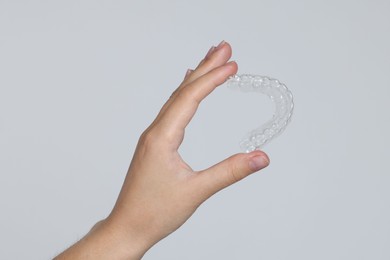 Photo of Woman with dental aligner on grey background, closeup