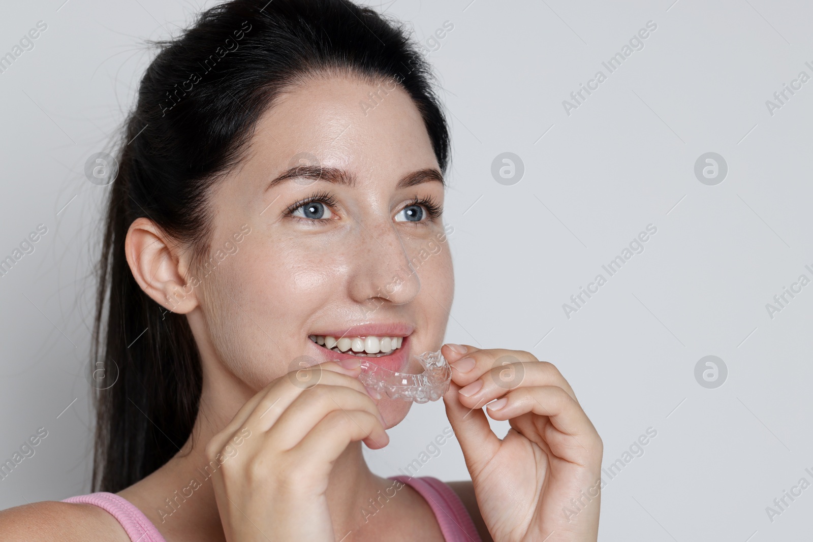 Smiling woman wearing dental aligner on grey background, closeup Photo of Smiling woman wearing dental aligner on grey background, closeup