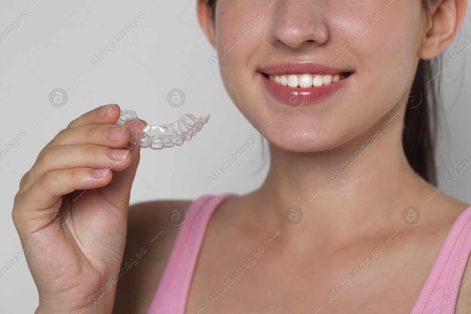 Smiling woman with dental aligner on grey background, closeup Photo of Smiling woman with dental aligner on grey background, closeup