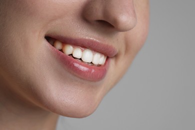Photo of Smiling woman after dental aligners treatment on grey background, closeup. Space for text