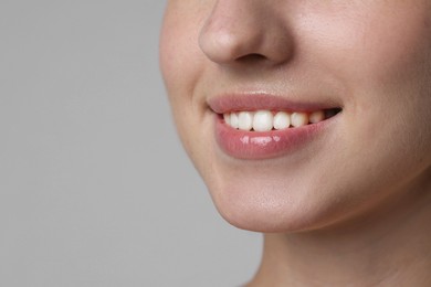 Photo of Smiling woman after dental aligners treatment on grey background, closeup. Space for text