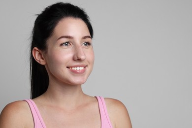 Photo of Smiling woman after dental aligners treatment on grey background. Space for text