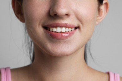 Photo of Smiling woman after dental aligners treatment on grey background, closeup