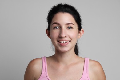 Photo of Portrait of smiling woman after dental aligners treatment on grey background