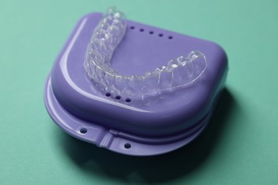 Photo of Clear aligner and retainer case on turquoise background, closeup