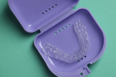 Photo of Clear aligner in retainer case on turquoise background, top view