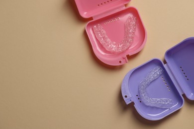 Photo of Clear aligners in colorful retainer cases on beige background, flat lay. Space for text