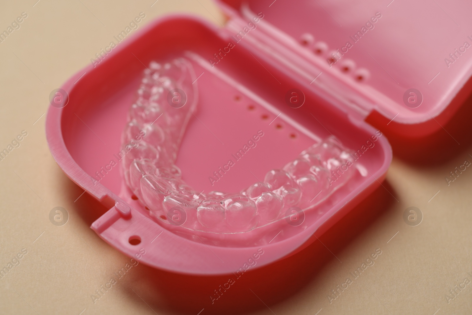 Clear aligner in retainer case on beige background, closeup Photo of Clear aligner in retainer case on beige background, closeup