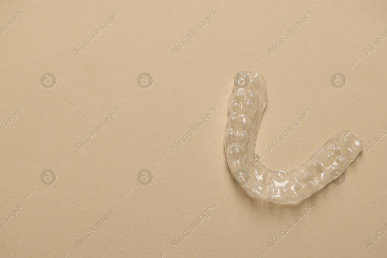 One clear aligner on beige background, top view. Space for text Photo of One clear aligner on beige background, top view. Space for text
