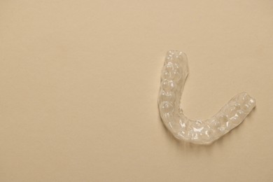 Photo of One clear aligner on beige background, top view. Space for text