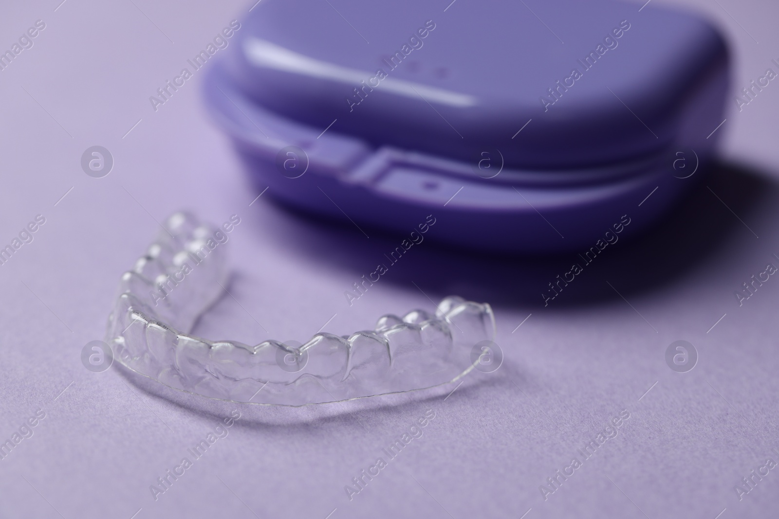 One clear aligner and retainer case on violet background, closeup Photo of One clear aligner and retainer case on violet background, closeup