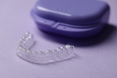Photo of One clear aligner and retainer case on violet background, closeup