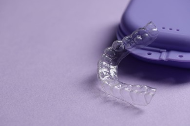 Photo of One clear aligner and retainer case on violet background, closeup. Space for text