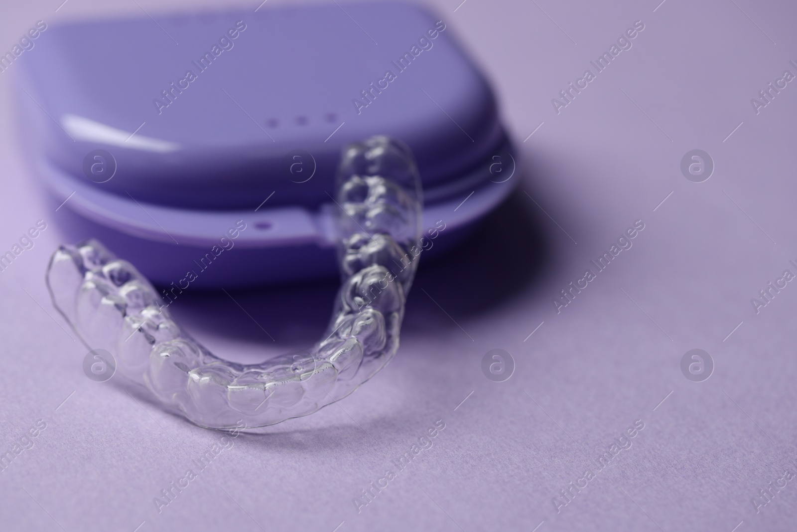 One clear aligner and retainer case on violet background, closeup Photo of One clear aligner and retainer case on violet background, closeup