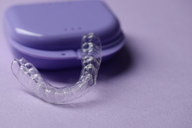 Photo of One clear aligner and retainer case on violet background, closeup